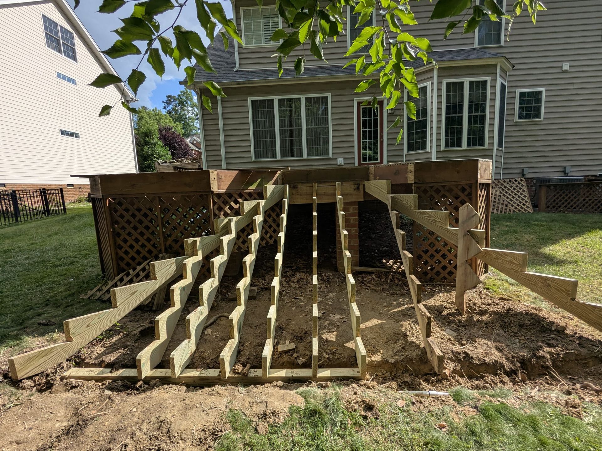 Wooden outdoor stairs under construction leading to a raised deck behind a house