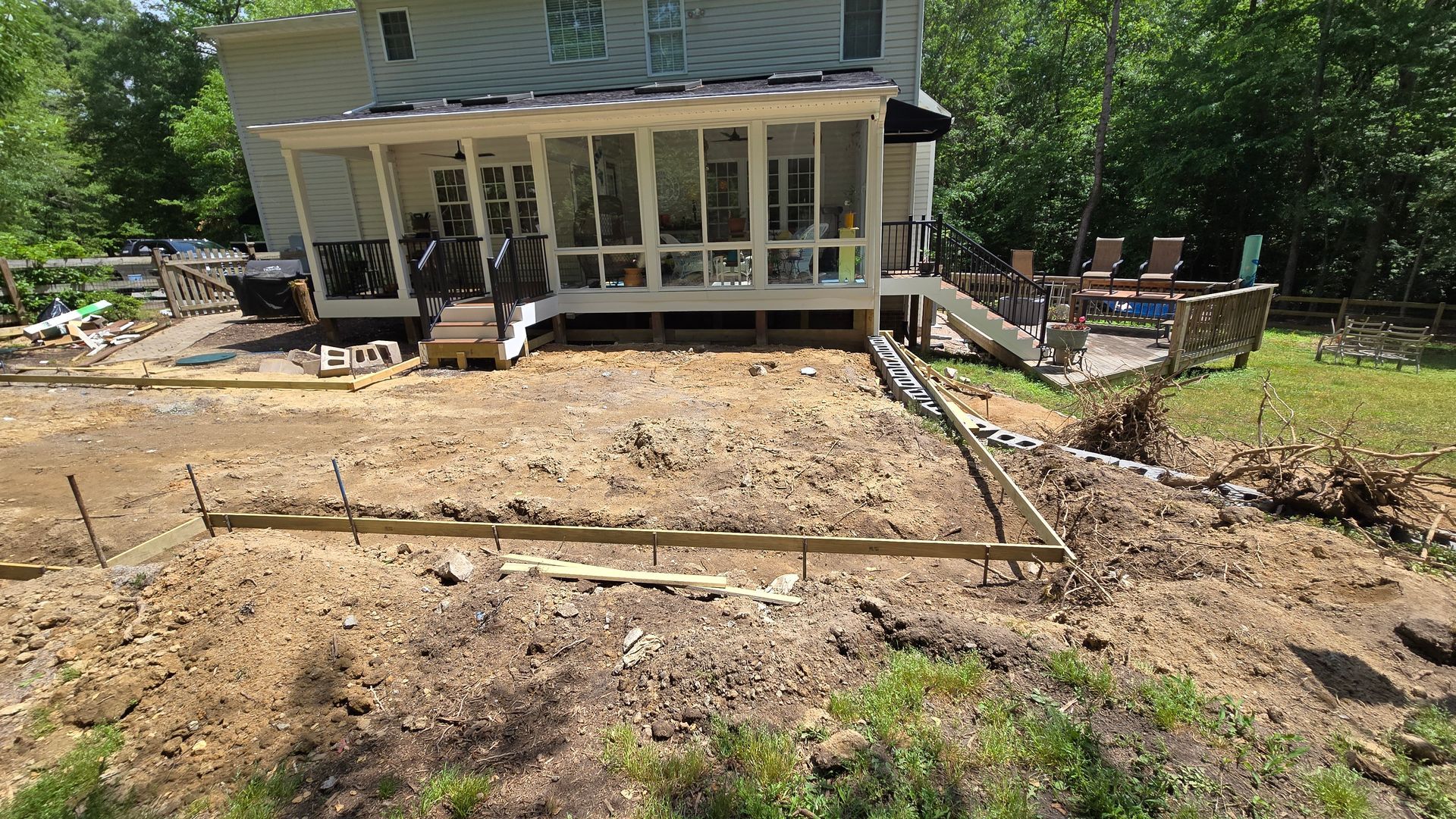 House with a screened porch overlooking a cleared dirt yard and construction site