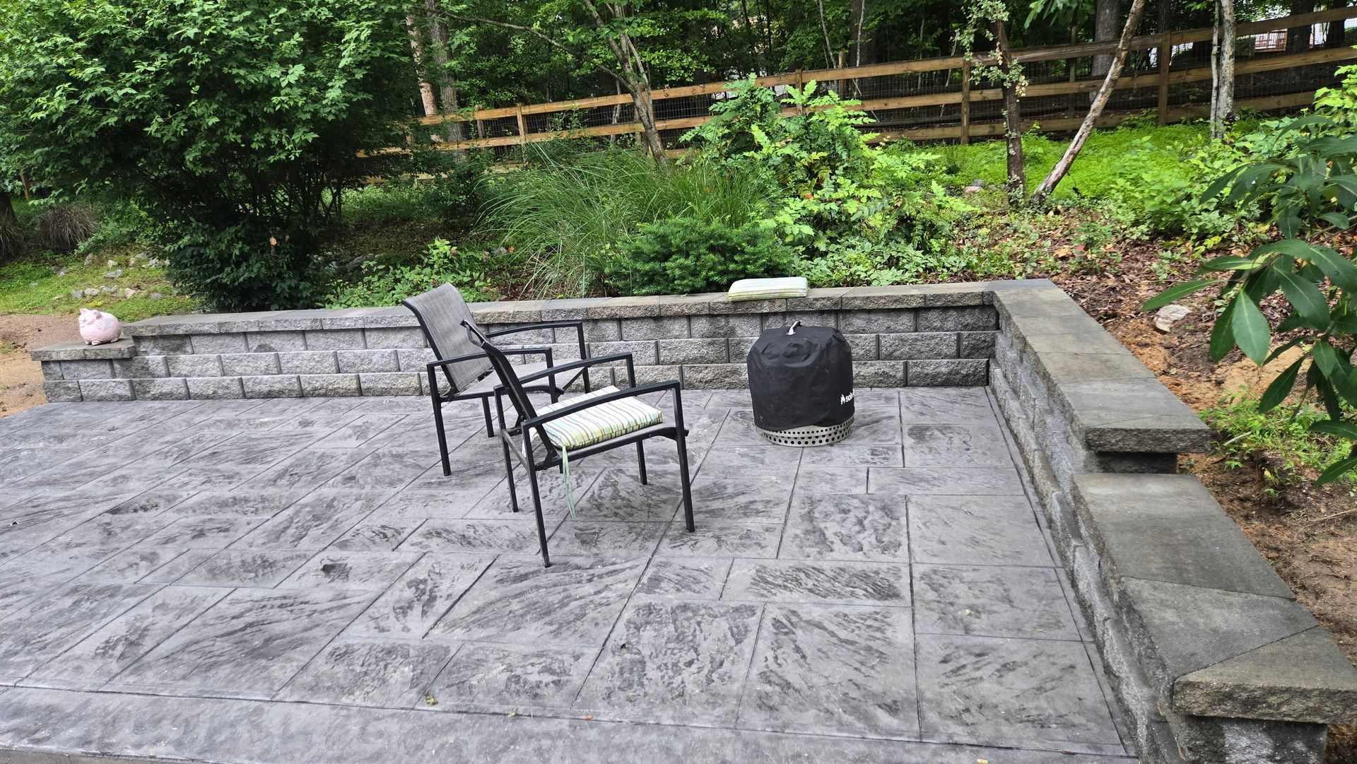 Stone patio with a metal chair and small table in a leafy backyard garden