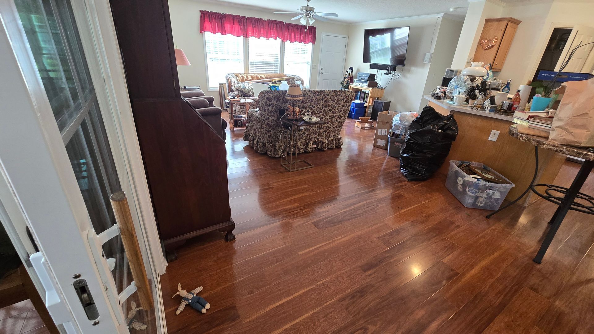 Wooden living room with recliner chairs, TV, and sunlight through a window, viewed from the entryway
