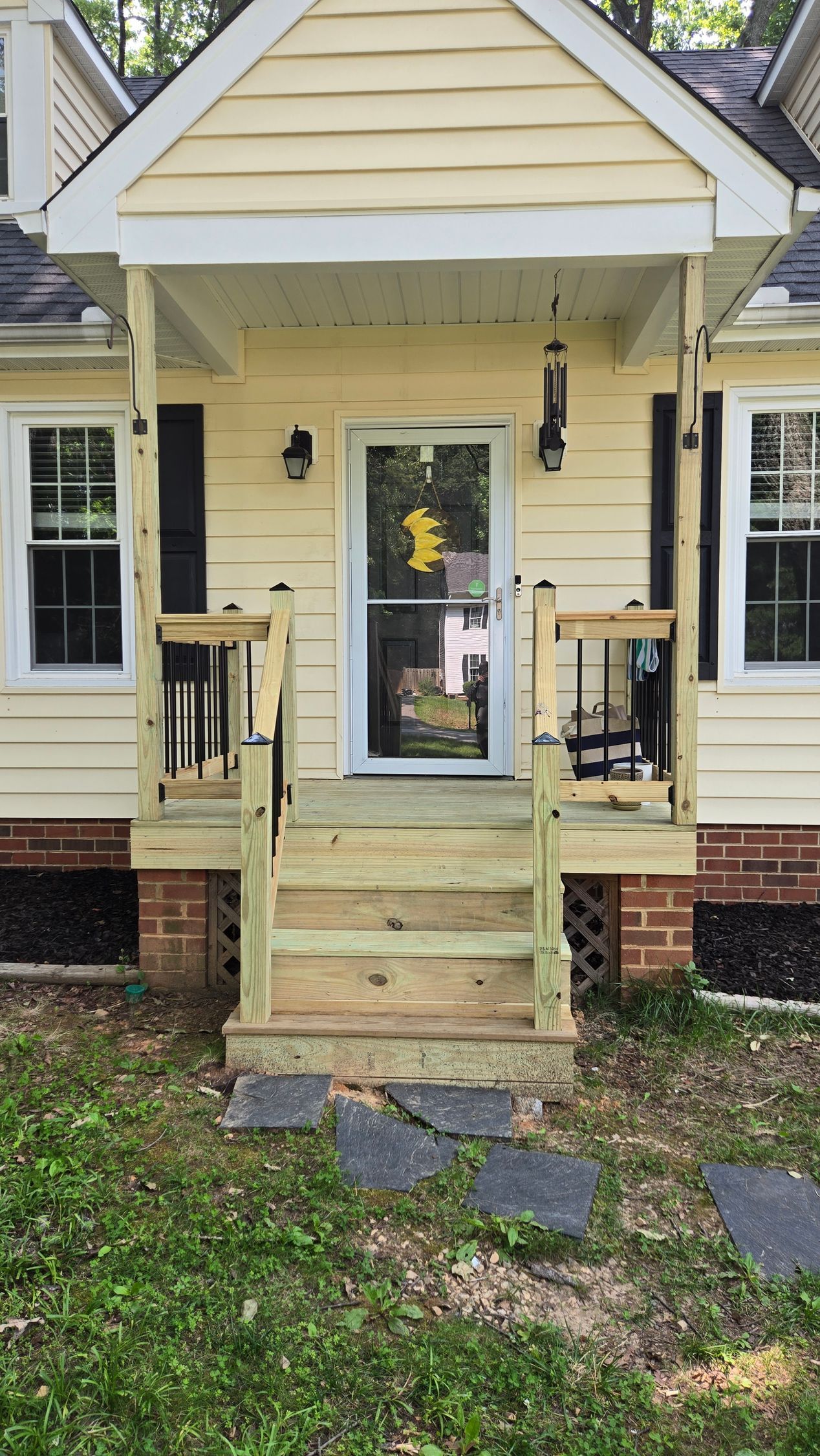 Front entrance of a yellow house with white trim, small porch, steps, and black lanterns