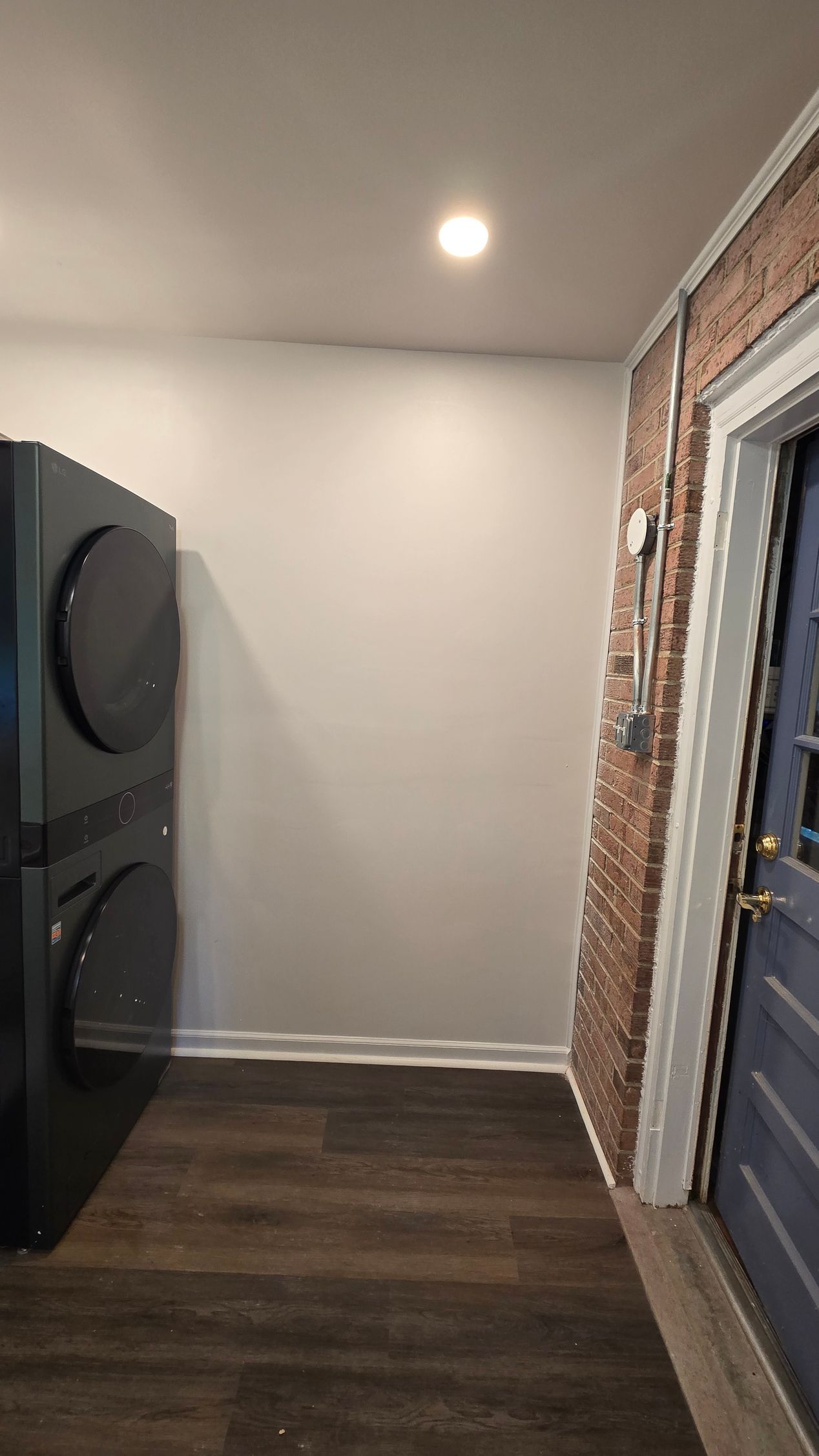 Small hallway with dark wood floor, white walls, recessed light, and a washer/dryer on the left.
