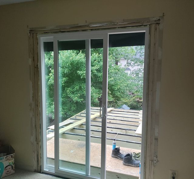 Sliding glass door opening onto a rooftop deck with trees visible outside
