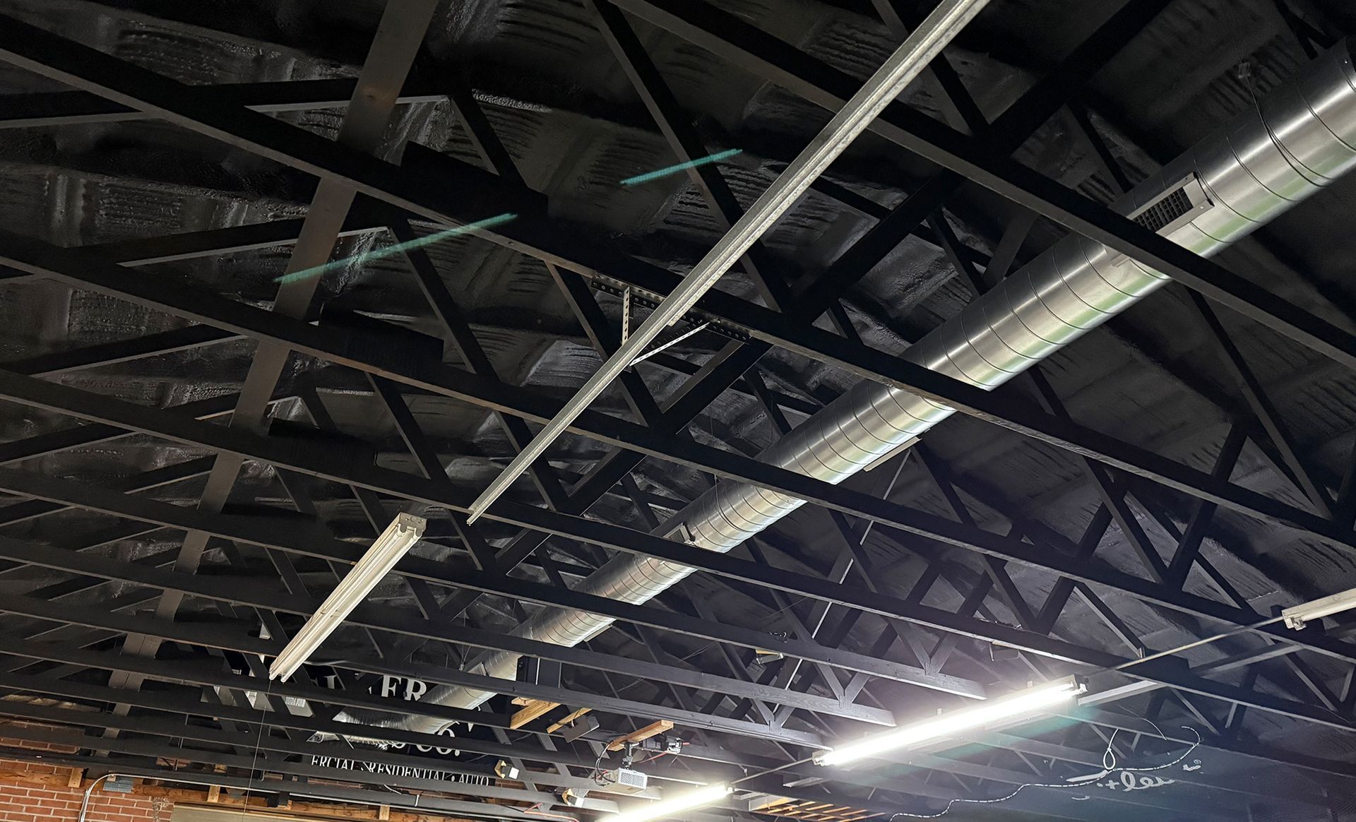 Dark metal truss ceiling with fluorescent lights.