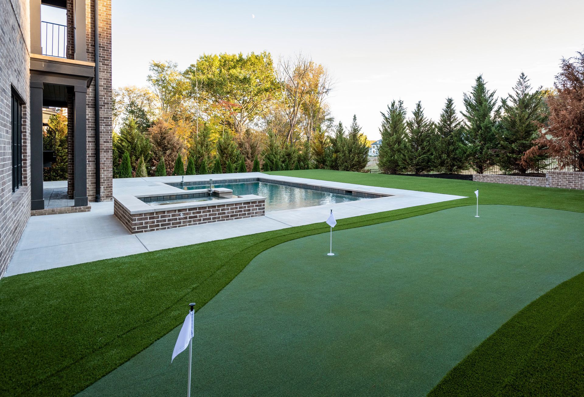There is a putting green in the backyard of a house.