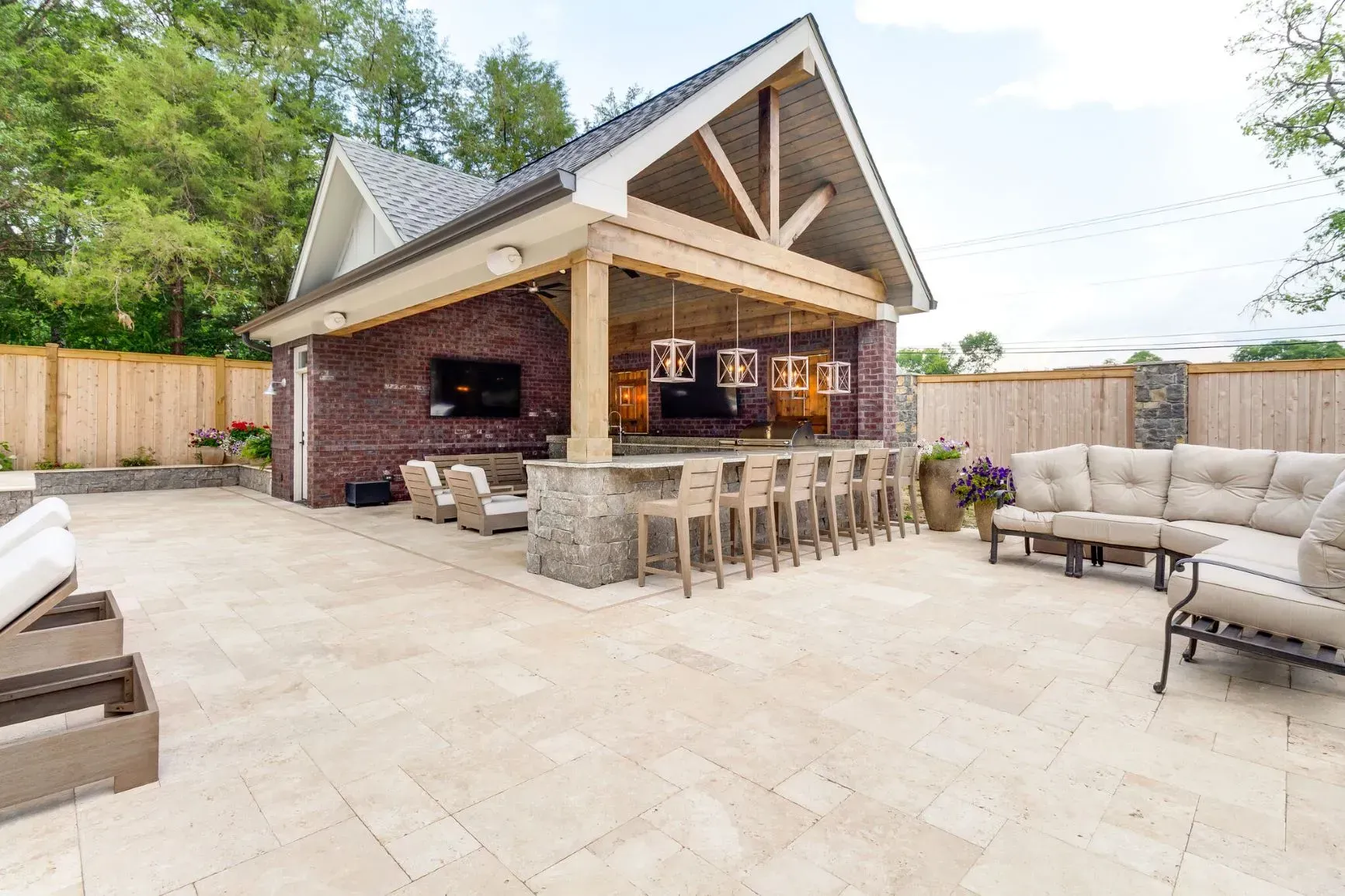 a patio with a couch , chairs , and a bar in front of a house