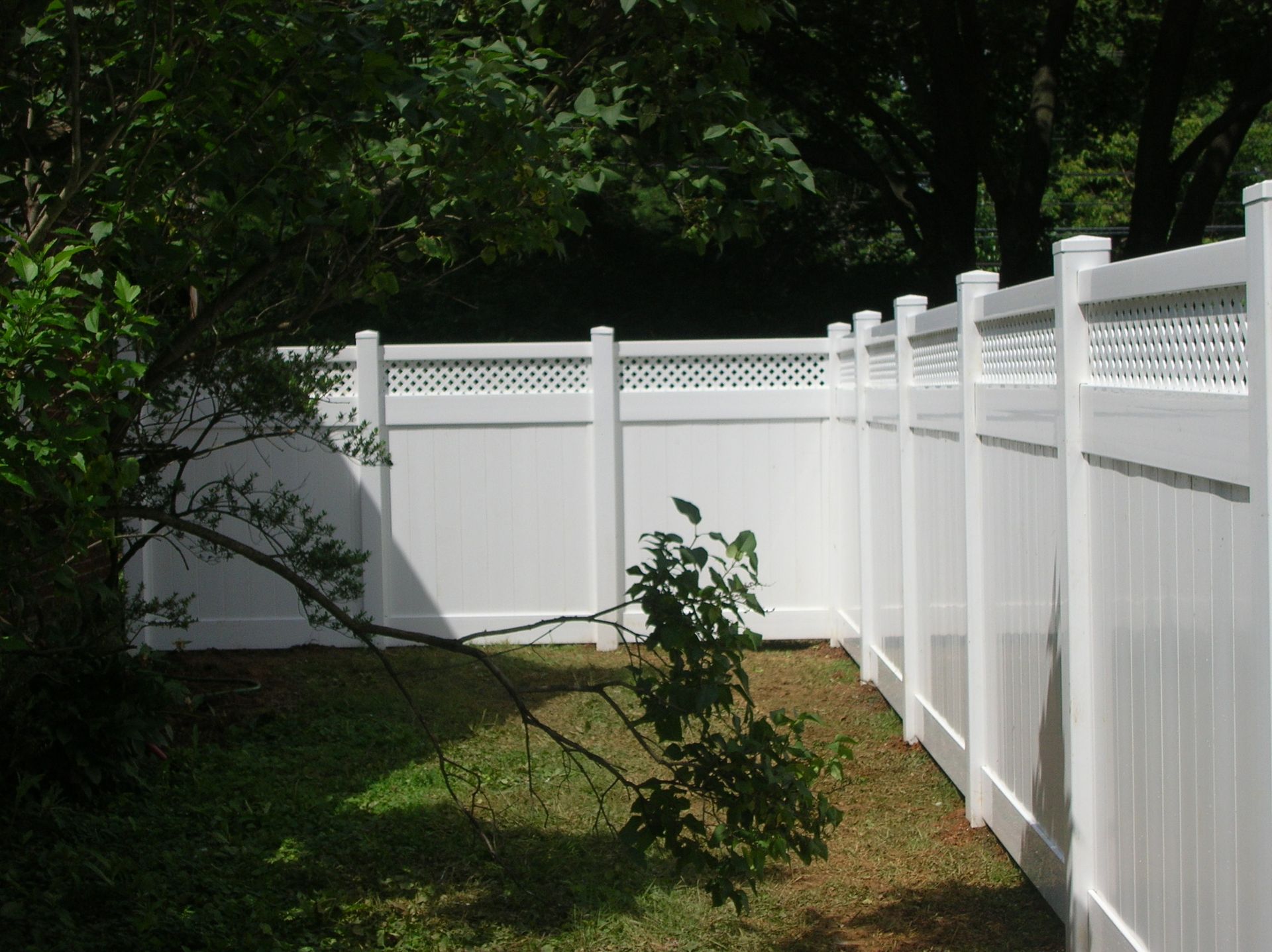 A white fence is surrounded by trees and grass