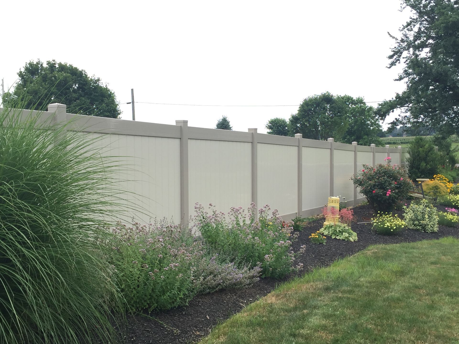 A white fence surrounds a lush green garden