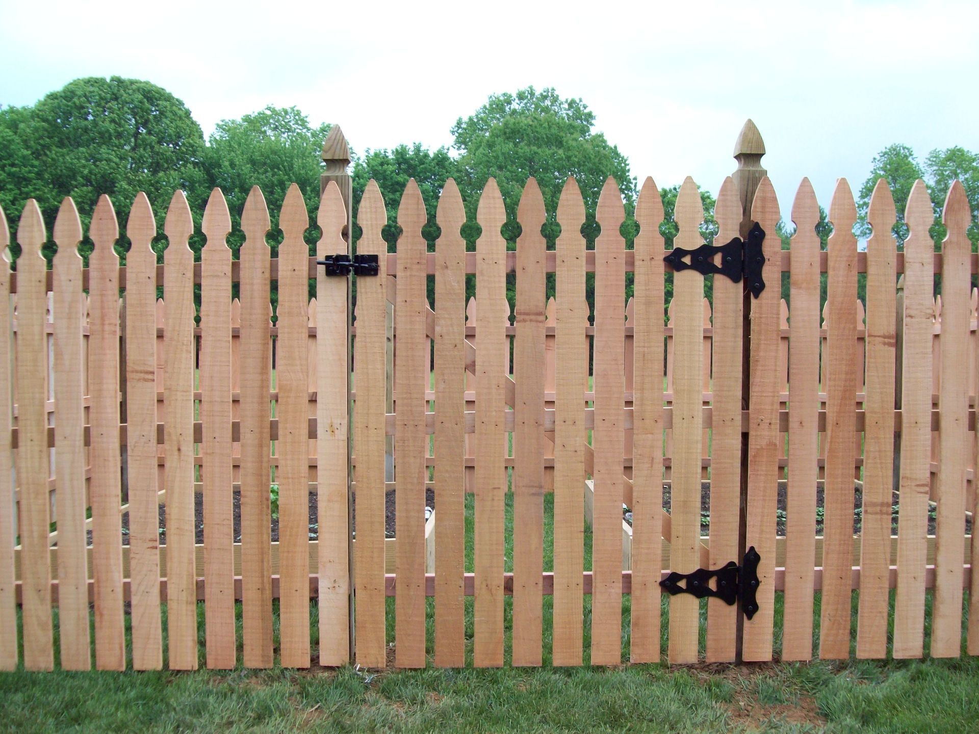 A wooden picket fence with a black gate