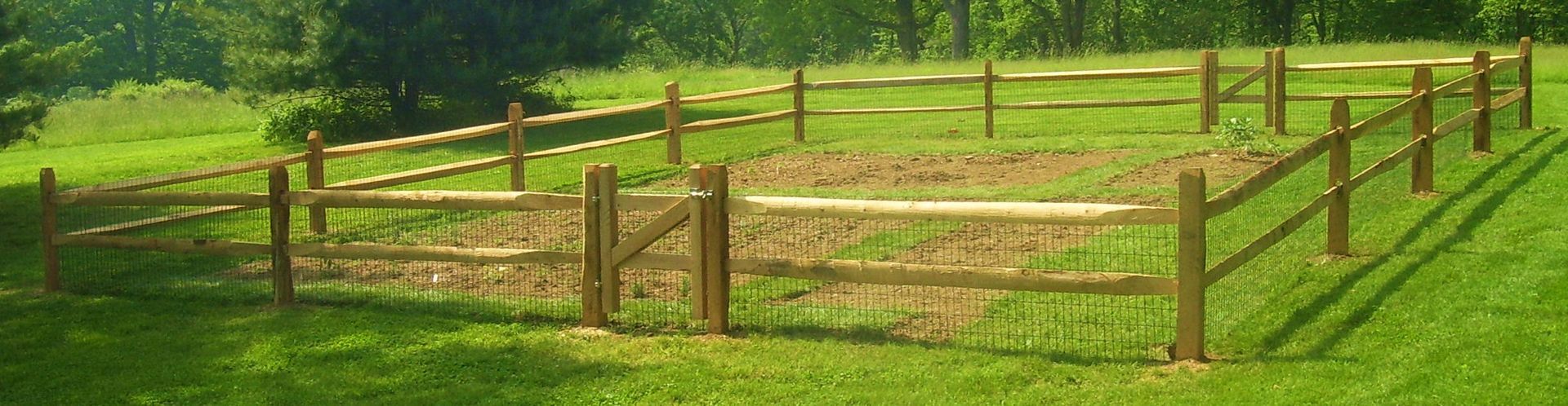 A wooden fence is in the middle of a grassy field.