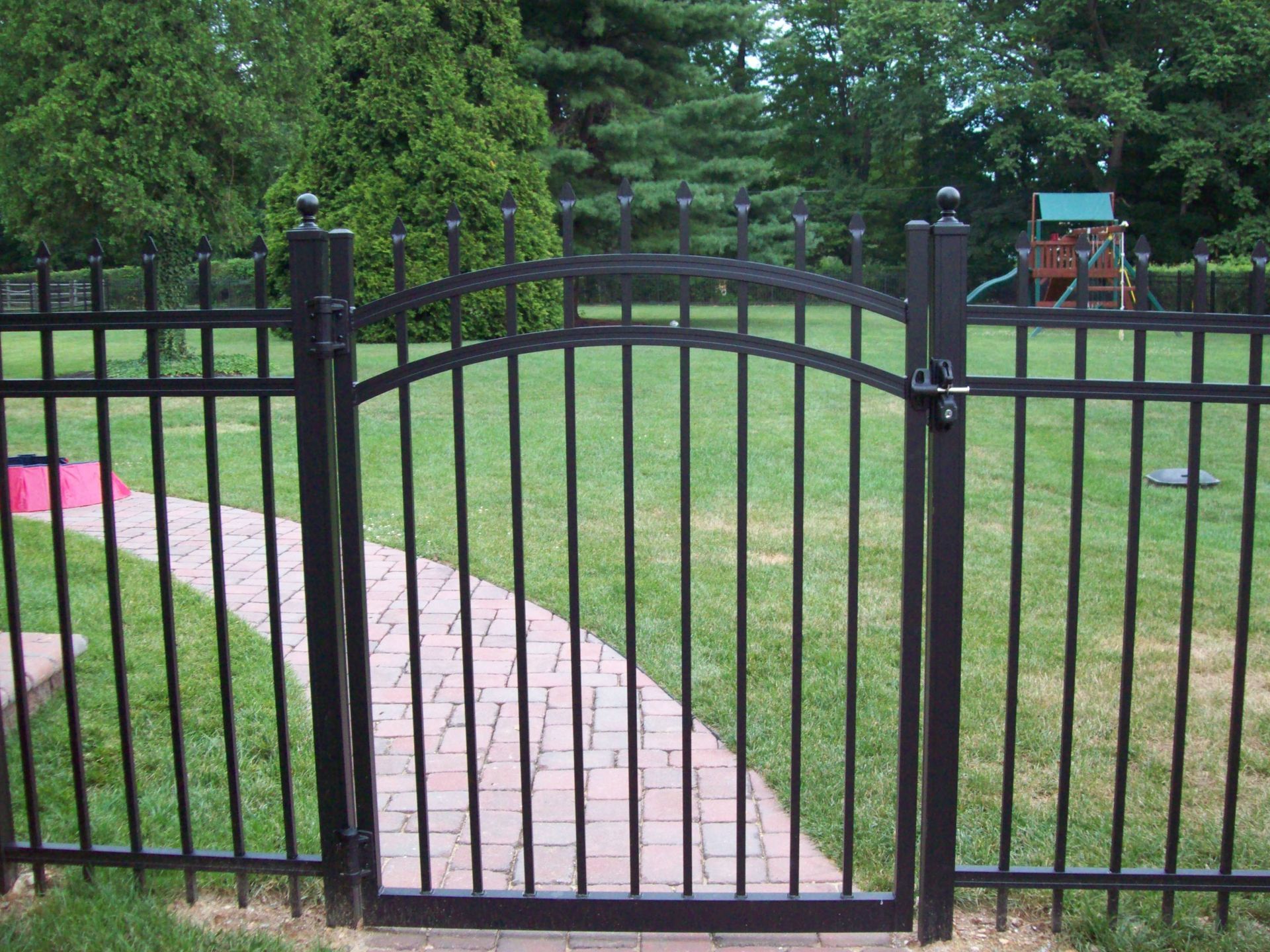 A black fence with a gate leading to a playground.