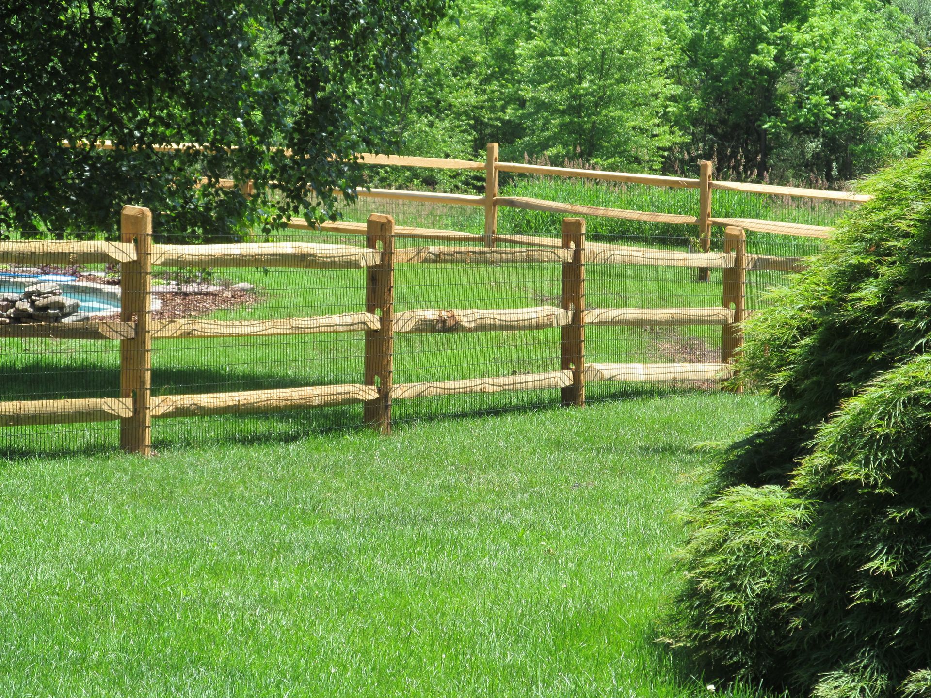A wooden fence surrounds a lush green field
