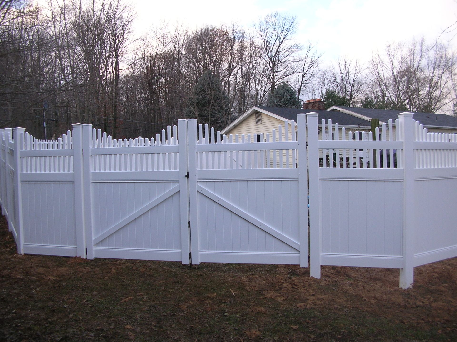 A white fence with a gate in front of a house