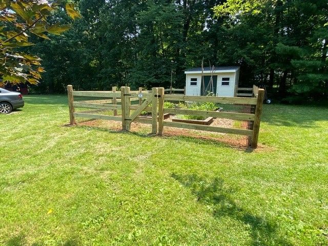 A wooden fence is in the middle of a lush green field.