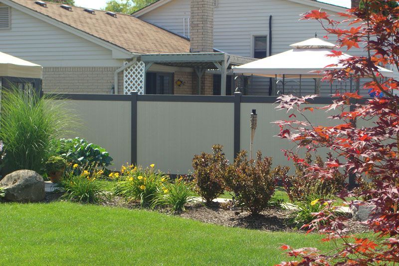 A backyard with a fence and a house in the background
