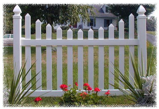 A white picket fence with red flowers in front of it