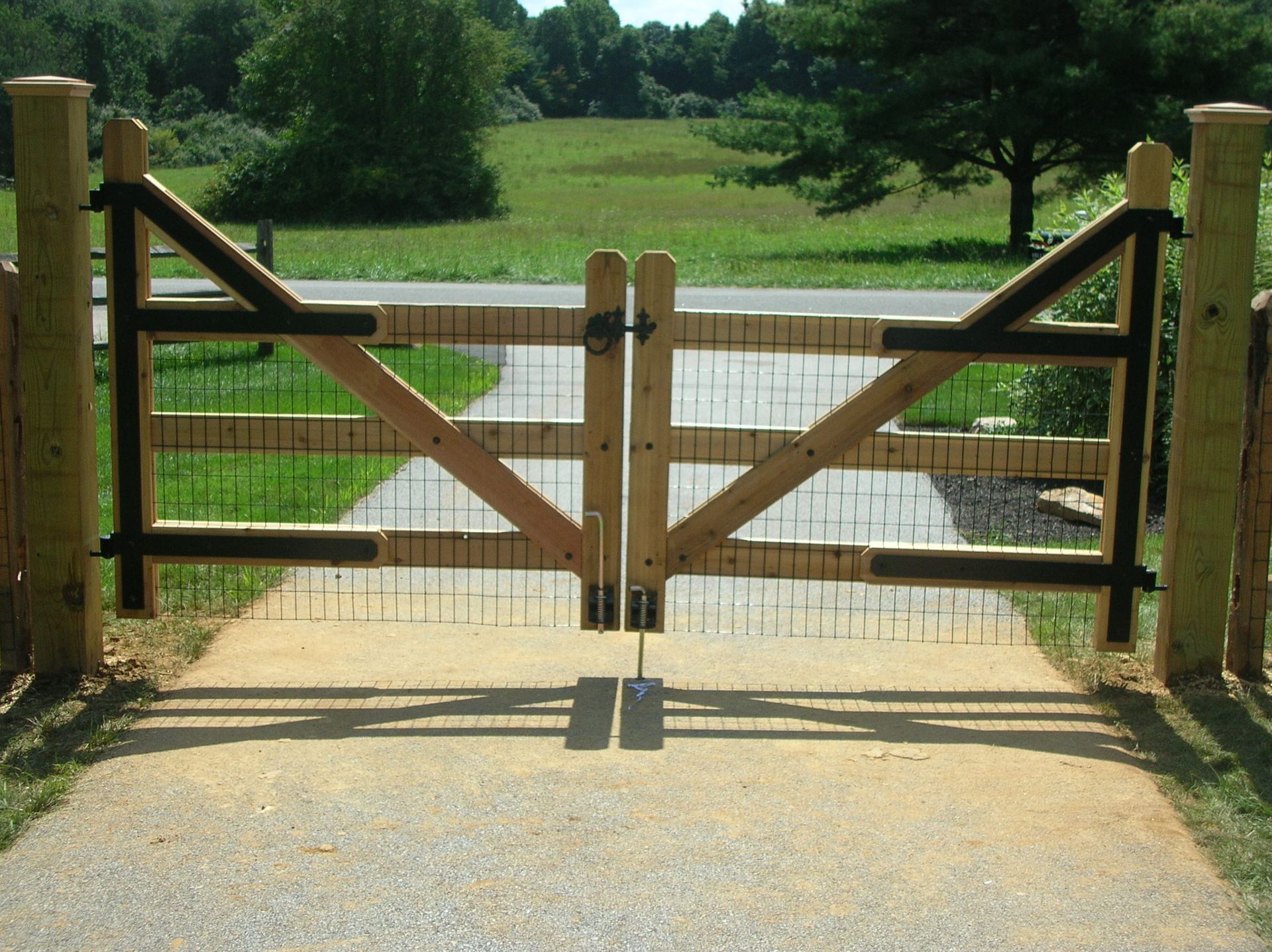 A wooden gate is open to a dirt path