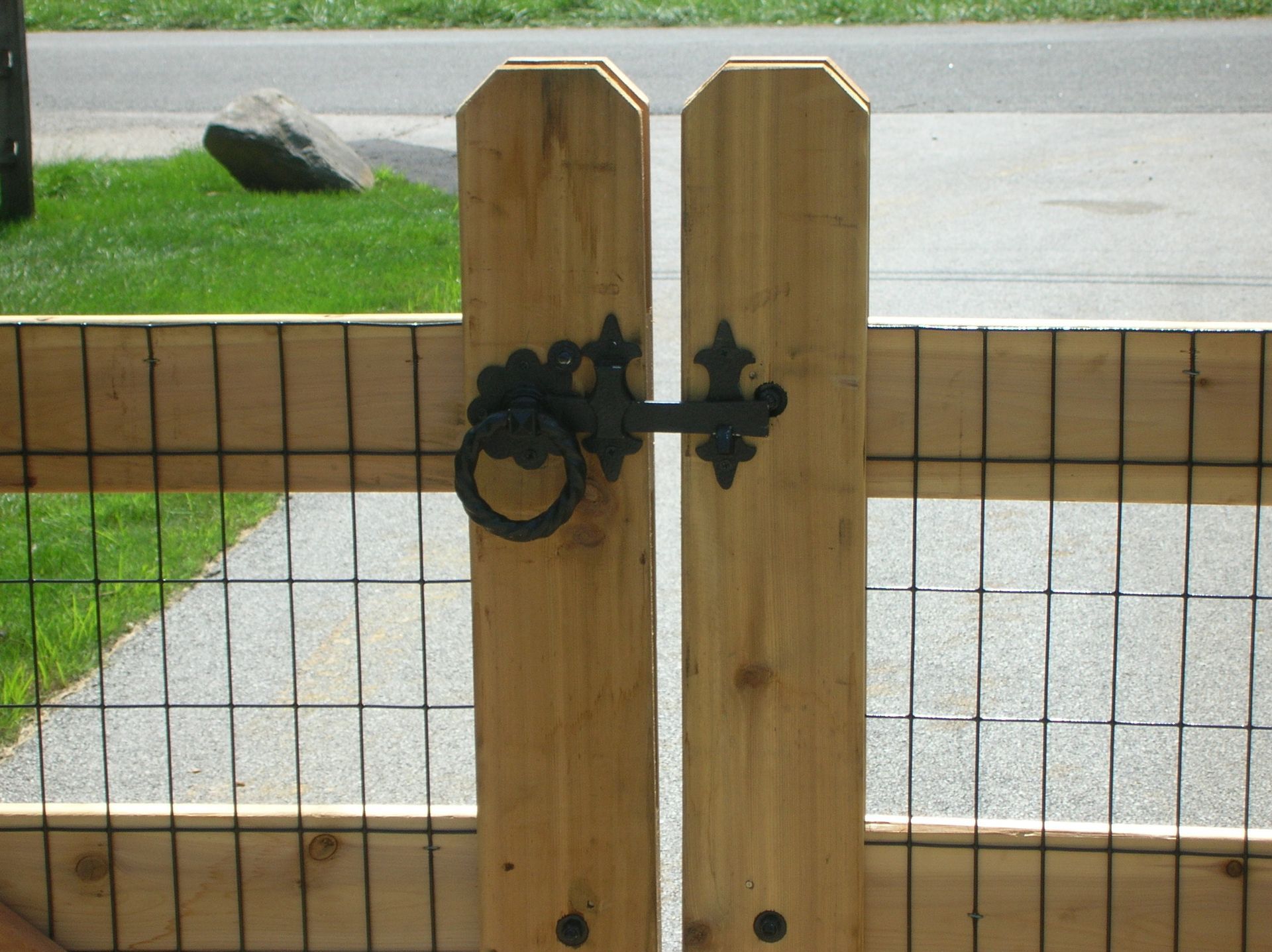A wooden gate with a metal fence behind it