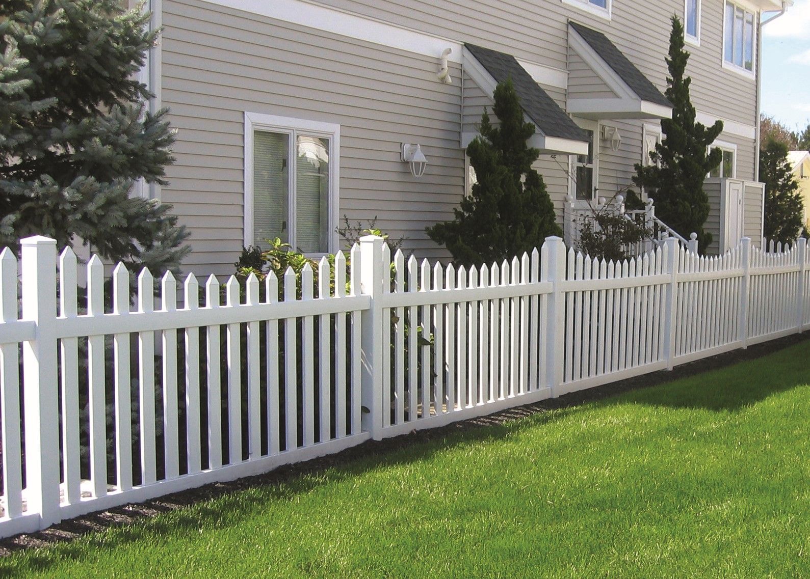 A white picket fence is in front of a house