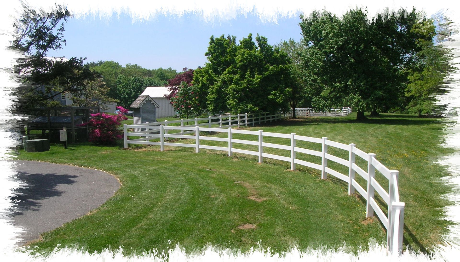 A white fence surrounds a lush green field