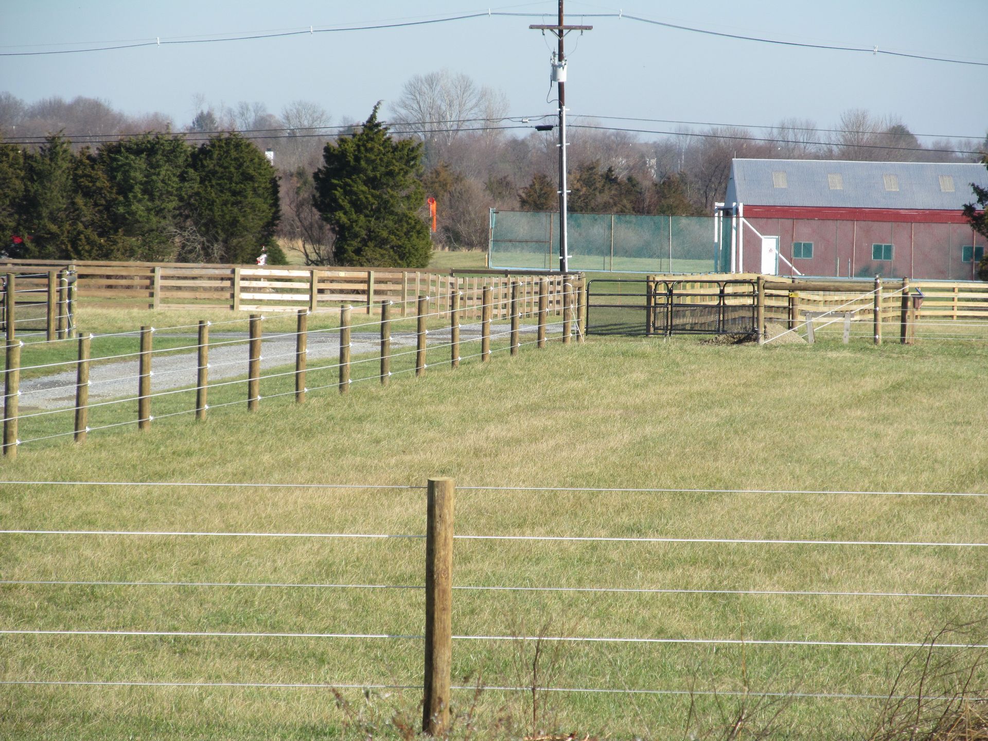 A fenced in field with a red building in the background