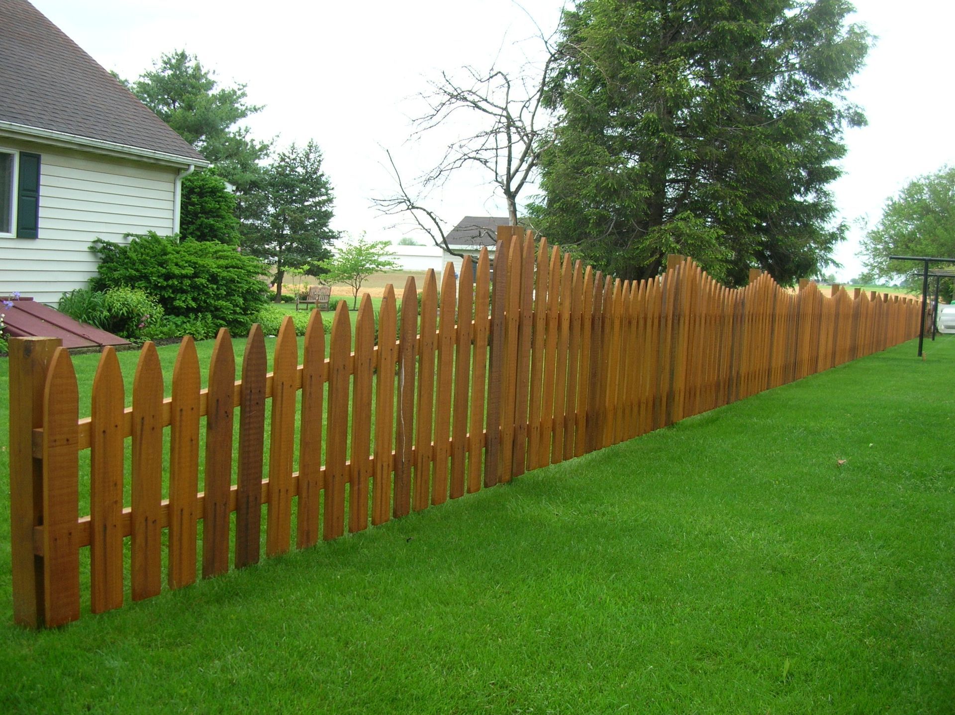 A wooden picket fence surrounds a lush green yard