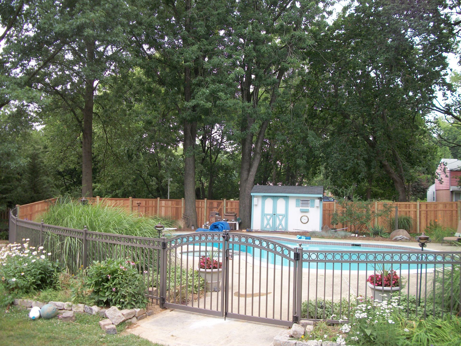 A fence surrounds a swimming pool in a backyard