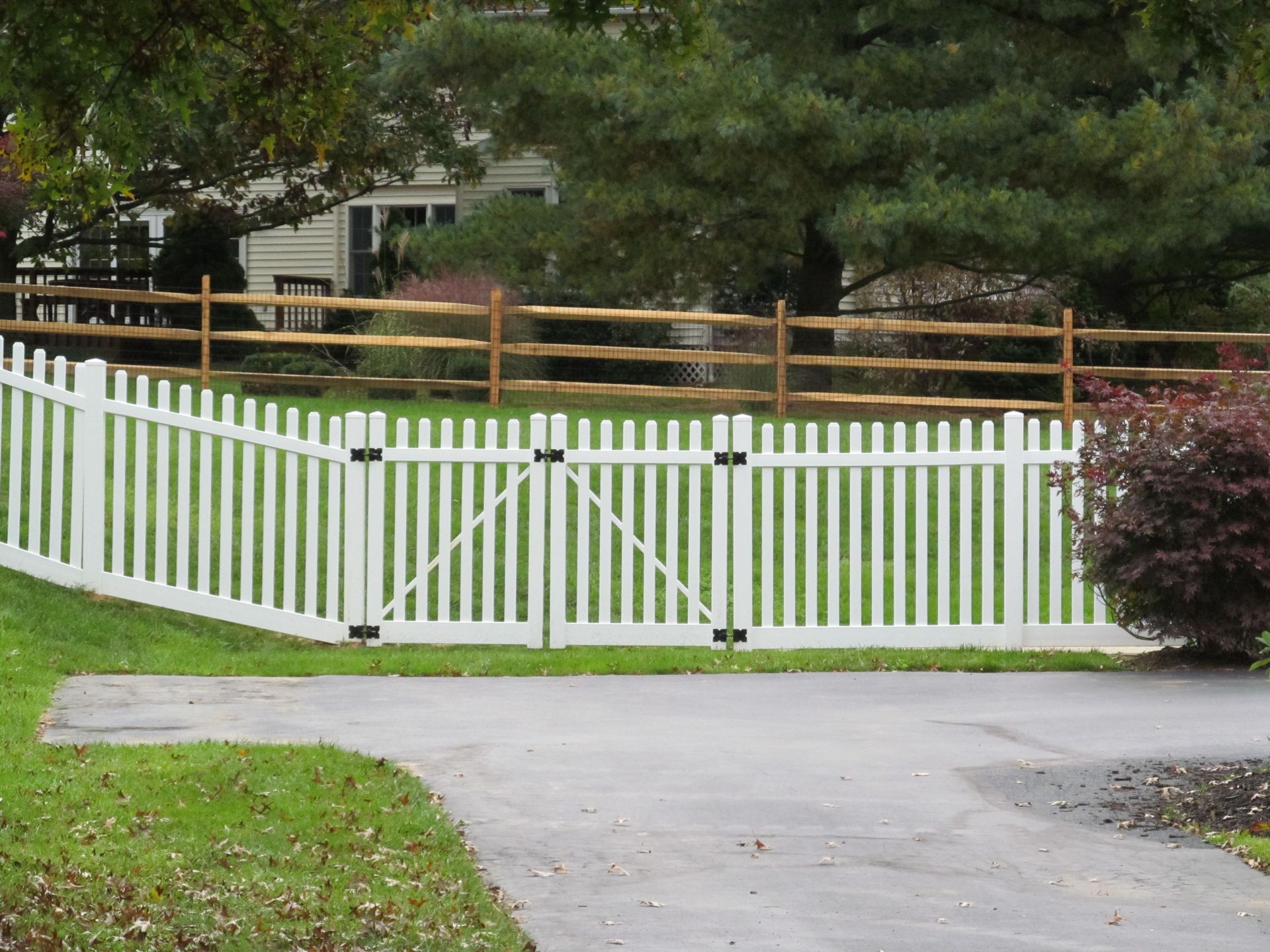A white picket fence with a wooden fence behind it