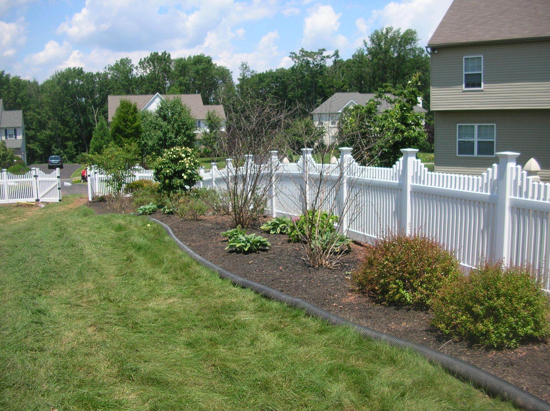 A white fence surrounds a lush green yard