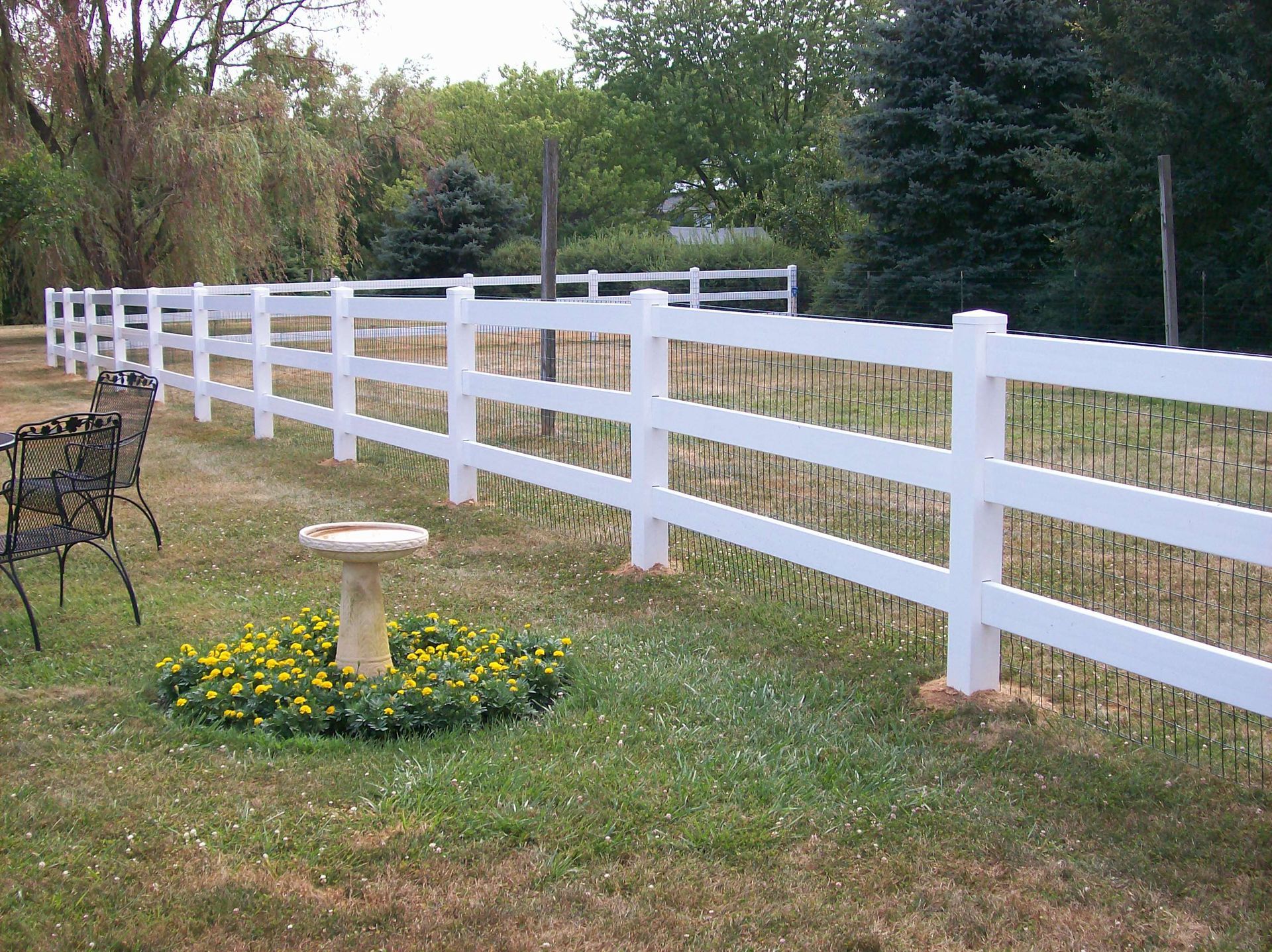 A white fence with a bird bath in the middle of it