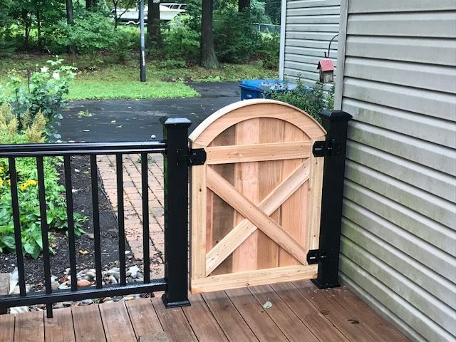 A wooden gate is sitting on a deck next to a house.