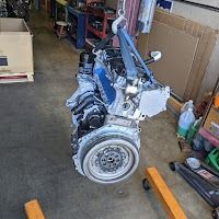 Engine suspended in a repair shop with lifting straps.
