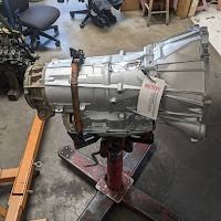 Silver automatic transmission on a red stand in a workshop.