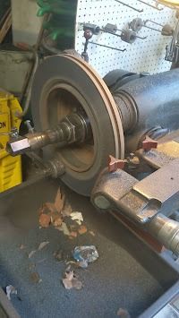 A brake rotor spinning on a lathe in a garage.