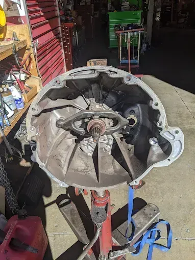 Open automotive transmission case on a red stand, indoors, shop setting.