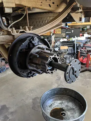 Truck axle assembly being worked on with a removed axle shaft, oil pan below.