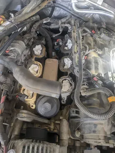 Engine bay with removed components; fuel injectors capped with white paper.