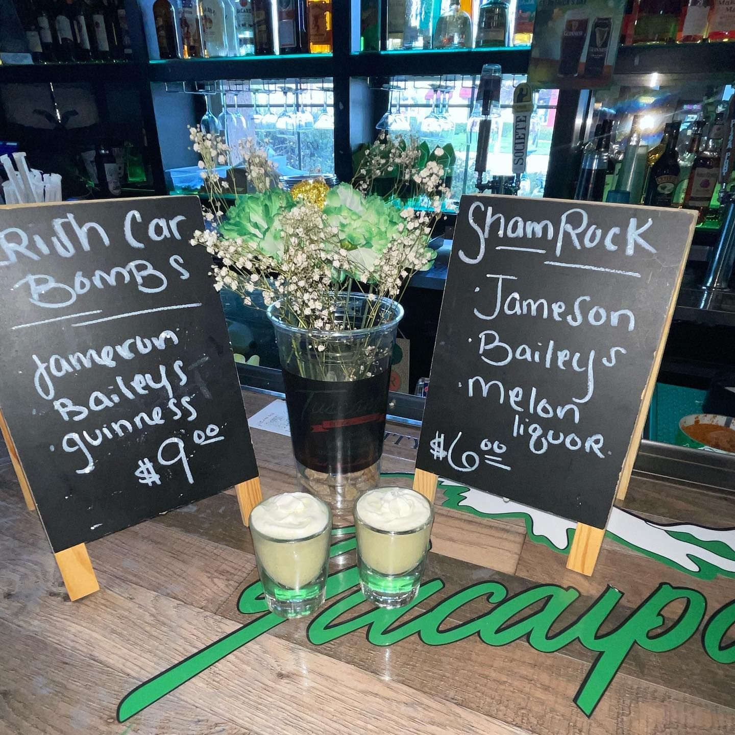 Two Irish shot drinks and chalkboards at a bar, advertising 