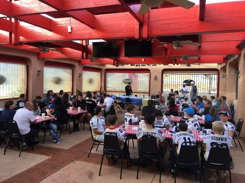 Large group in a red-roofed outdoor space; people seated at tables, likely a team gathering or event.