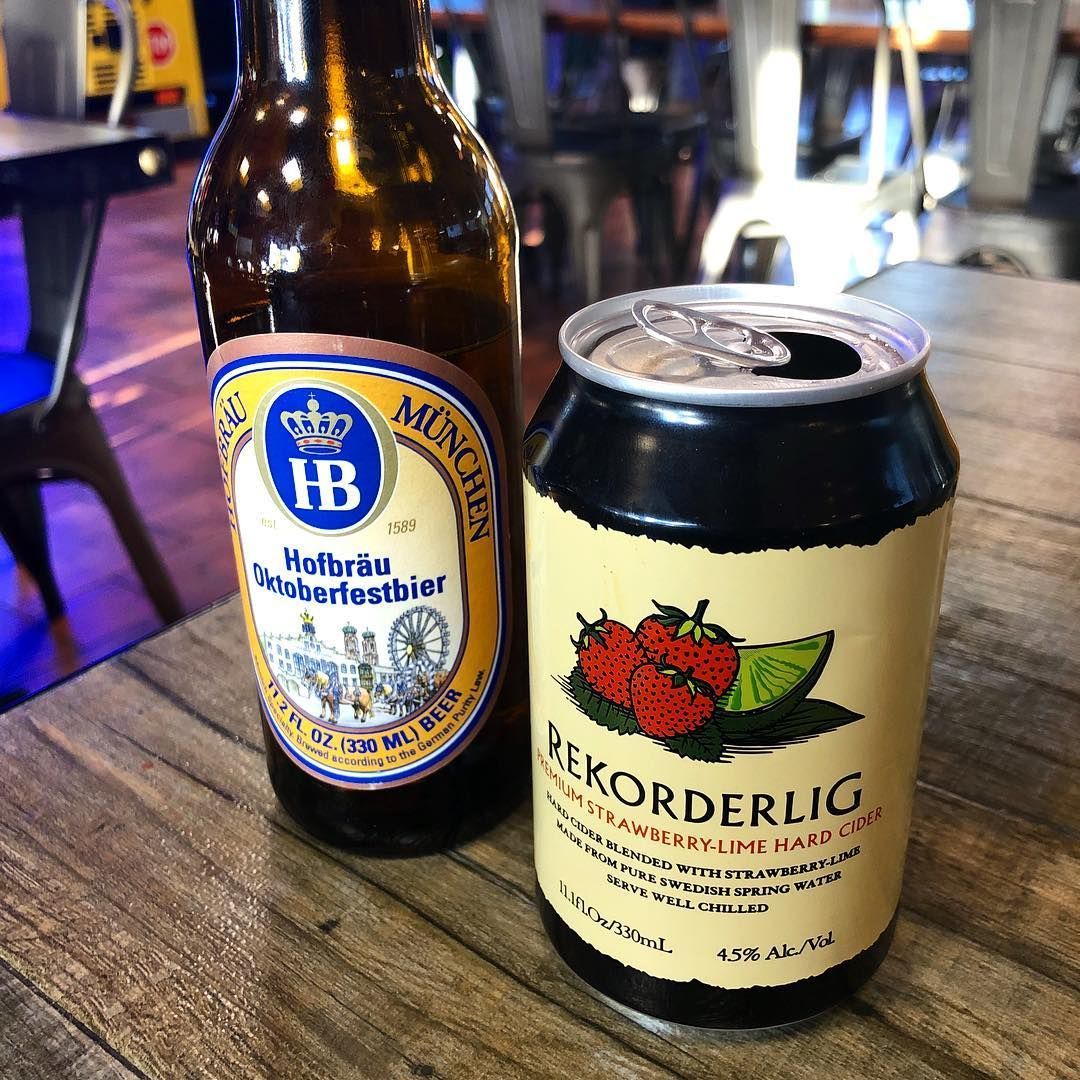 Bottle of Hofbräu beer and a Rekorderlig cider can on a wooden table.