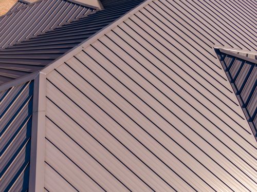 Close-up of a modern building roof with tan metal panels and dark trim.
