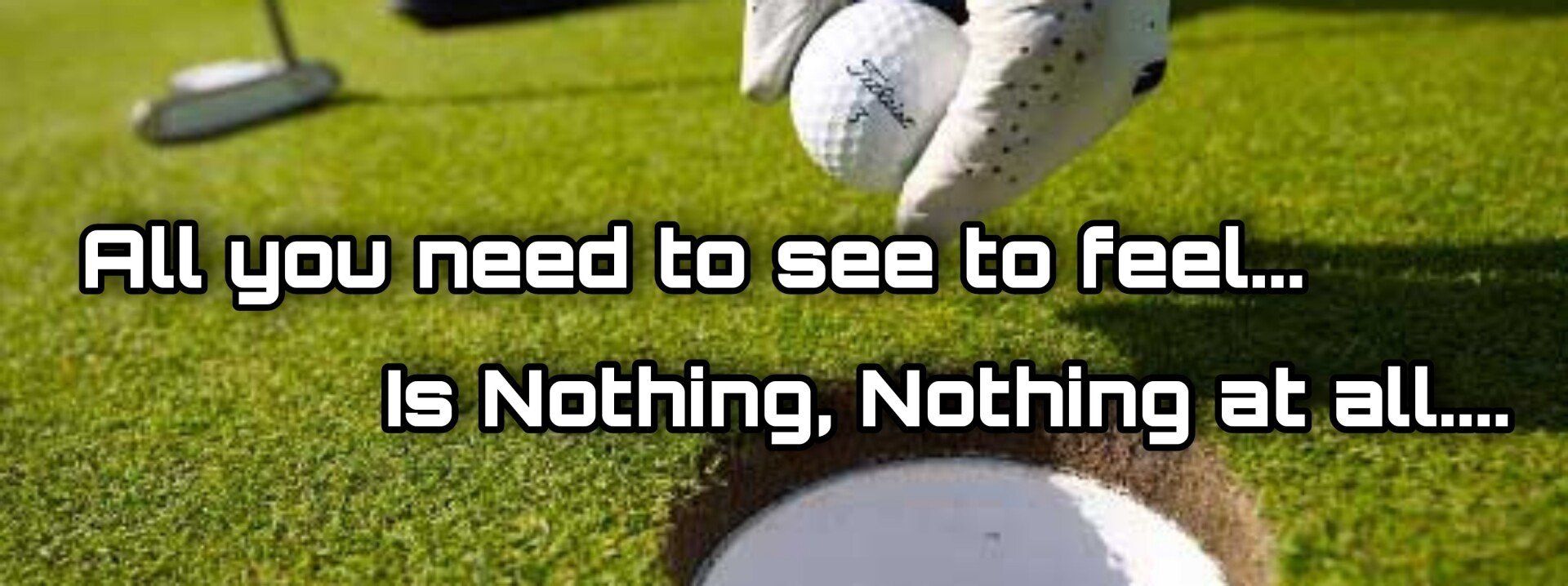 A golfer is placing a ball into the hole on green grass.