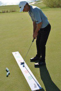 Golfer practicing putting on a green with an alignment aid; focused expression.
