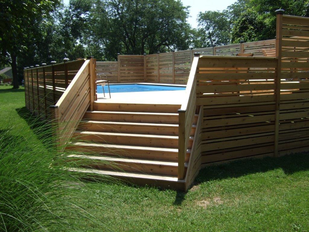 A wooden deck with stairs leading to a swimming pool