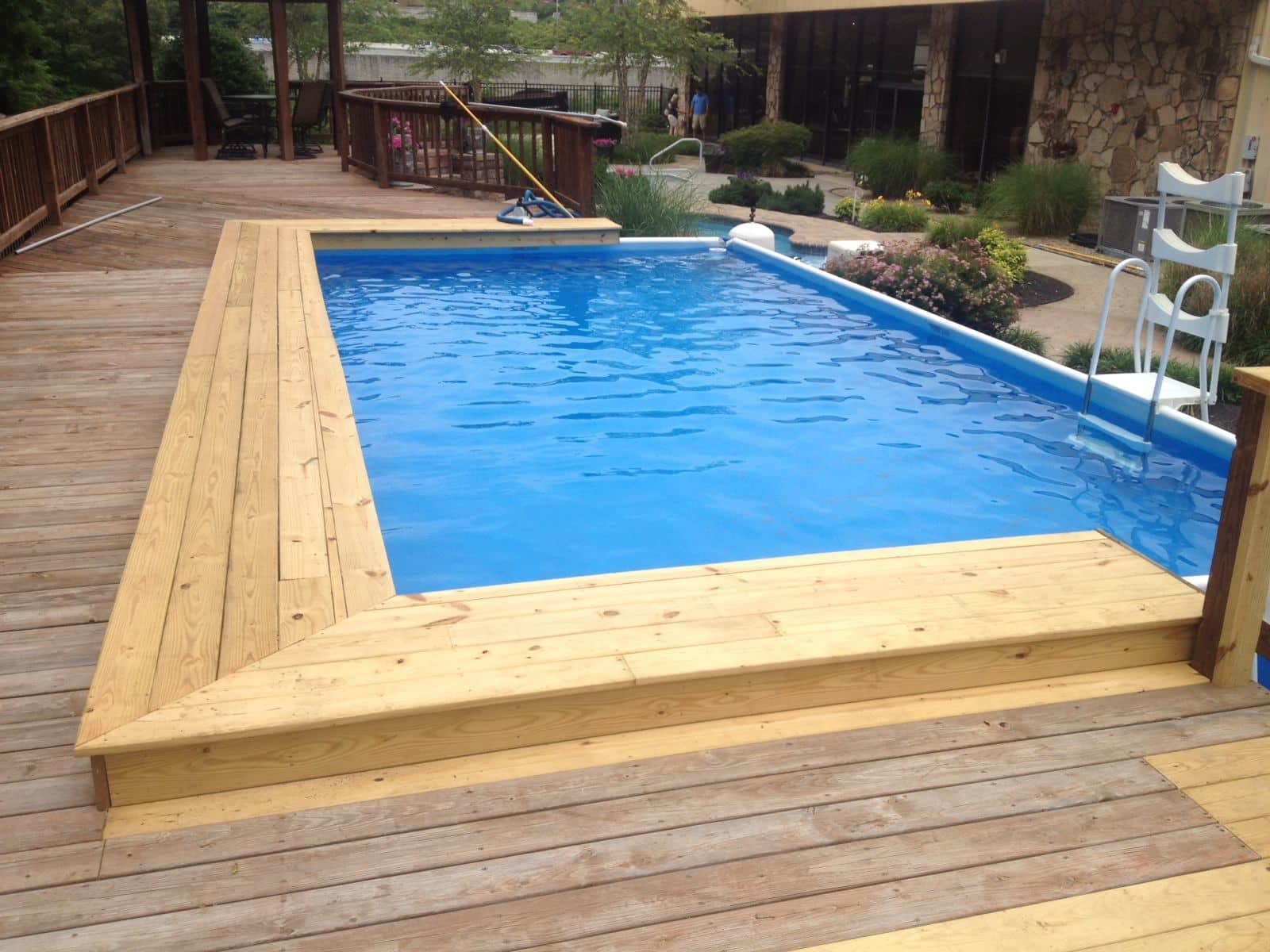 A large swimming pool is surrounded by a wooden deck.