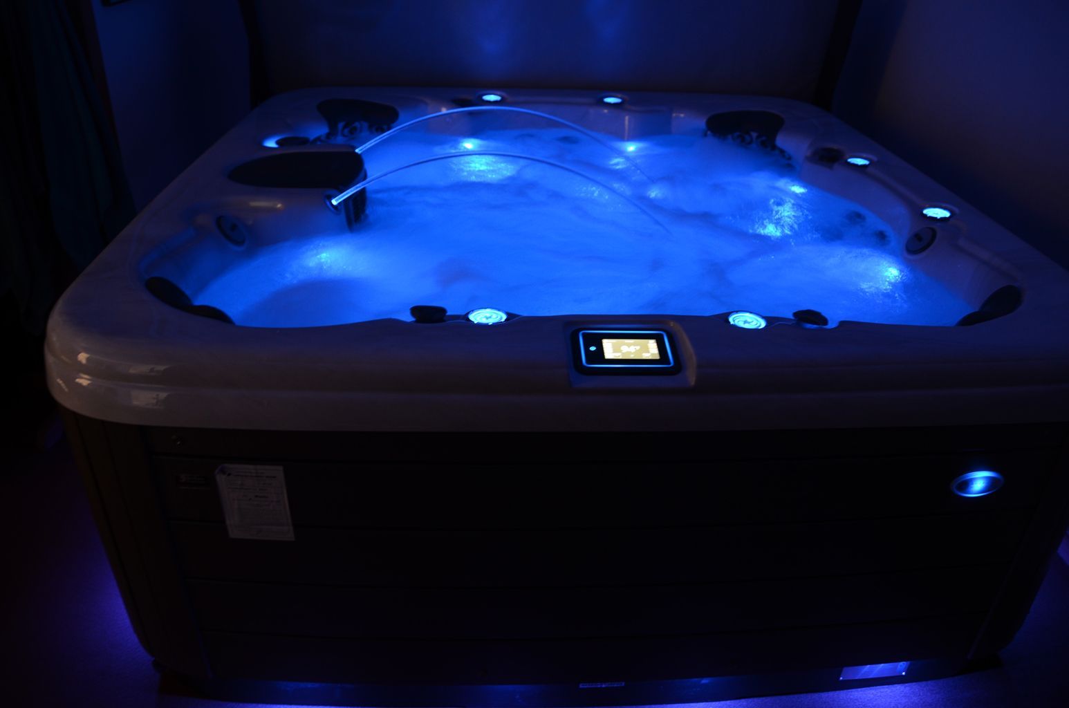 A hot tub is lit up with blue lights in a dark room