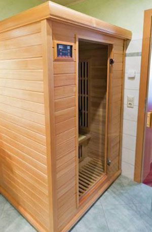 A wooden sauna is sitting in a bathroom next to a door.