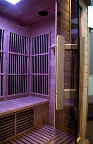 A wooden sauna with a purple light on the ceiling.