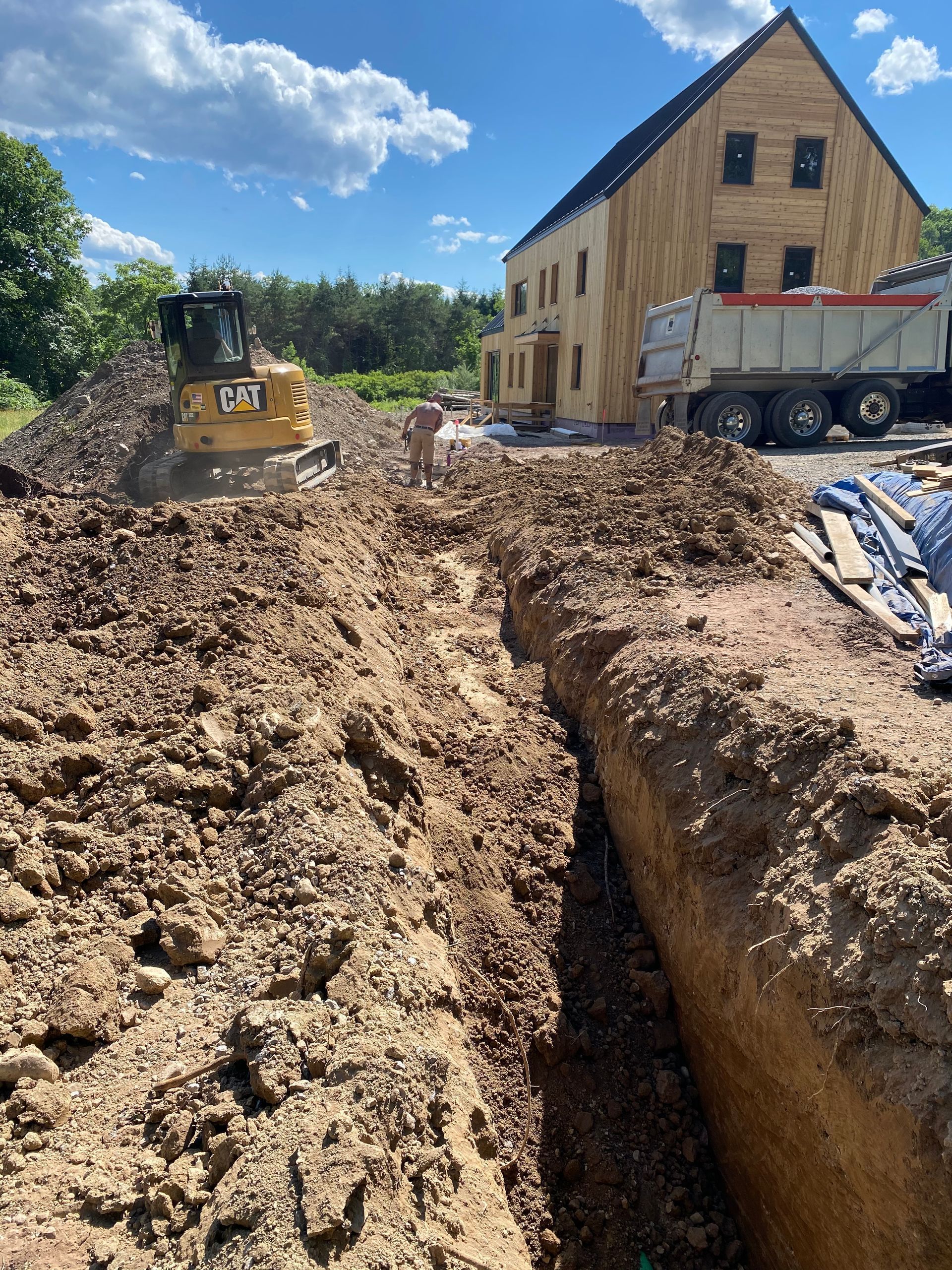 A bulldozer is digging a hole in the dirt in front of a house.