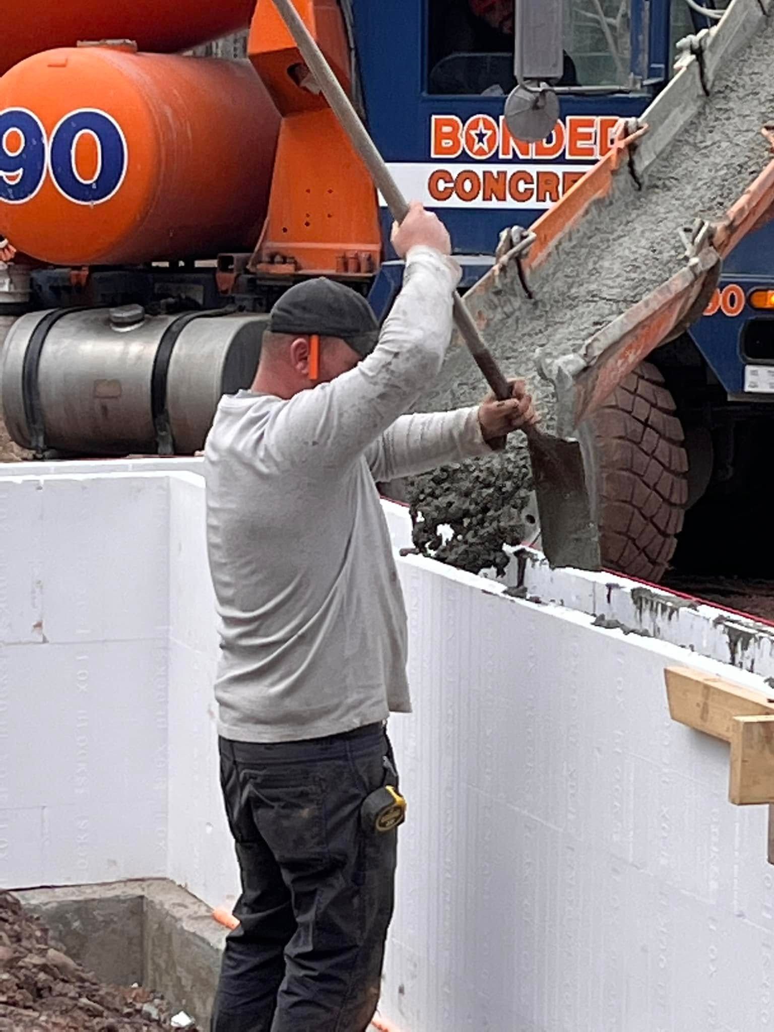 A man is pouring concrete into a concrete wall.